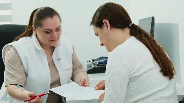 Woman patient signs medical consent form with doctor help in clinic slow motion. Professional healthcare service provided by hospital
