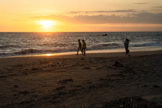 Sri Lanka - 11 January 2026: View of people walking along the sandy beach during a golden sunset.