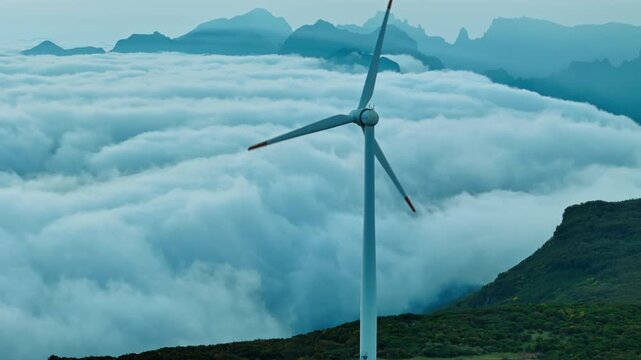 Wind turbine on elevated terrain above clouds, renewable energy sector development in Madeira, Portugal