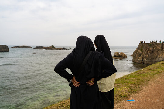Sri Lanka - 07 January 2026: View of two women in traditional Muslim attire looking at the Indian Ocean from the historic ramparts of Galle Fort.