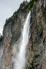 Obraz premium Dramatic alpine waterfall flowing over rocky cliff in Switzerland.
