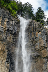 Obraz premium Majestic waterfall cascading down rocky cliff in Swiss Alps.