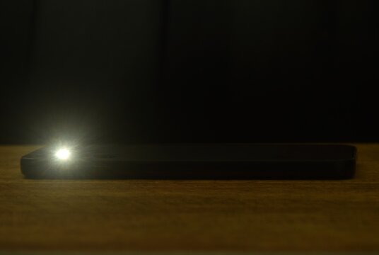 flashlight of mobile phone on table in dark night