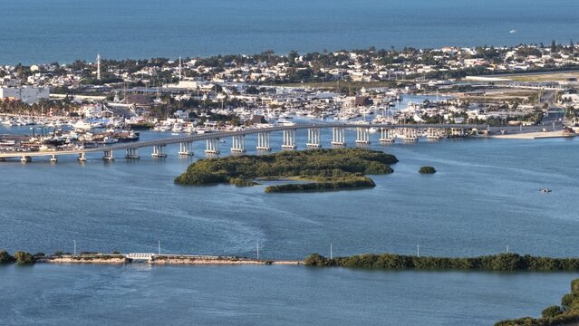 Aerial view of Yucalpeten bridge spanning the blue lagoon waters with boats in the marina and lush green mangroves Progreso, Yucatan, Mexico.