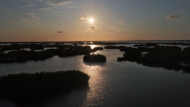 Aerial view of Yucalpeten lagoon with mangrove islands and golden sunset reflections on the water in Progreso, Yucatan, Mexico.