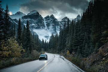 Fototapeta premium Scenic mountain road through pine forest toword Canadian Rockies Peak in Banff national park, Canada