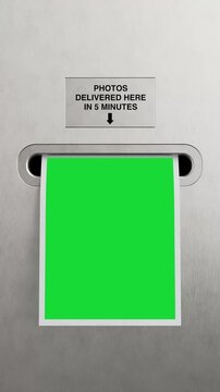 4k Resolution Vertical Video for Social Media: Instant Photo Printing Service Concept With Photo Booth Output Slot. Blank Green Screen Photo Template Coming Out Of Machine Extreme Closeup
