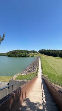 CELJE, SLOVENIA - MAY 23, 2026: Vertical 4K real-time POV video of walking on a concrete dam path at Smartinsko Jezero lake