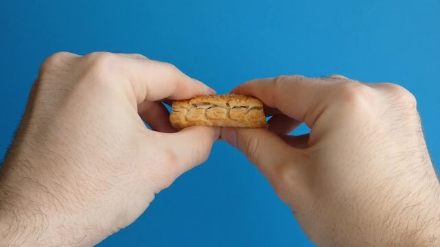 Hands breaking crispy puff pastry cookie with sweet raspberry jam filling
