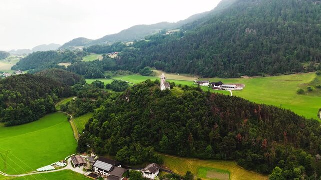 Chiesa di Santa Verena in a rural valley of the Dolomites, aerial view. South Tyrol church within farmland and pasture parcels
