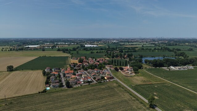Aerial View of Italian Countryside: An expansive drone shot captures the picturesque Italian countryside, showcasing a cluster of terracotta-roofed houses, verdant agricultural fields.