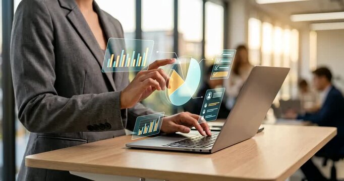 A woman hand pointing on a hologram charts above laptop in office, AI automation in business workflows data analysis