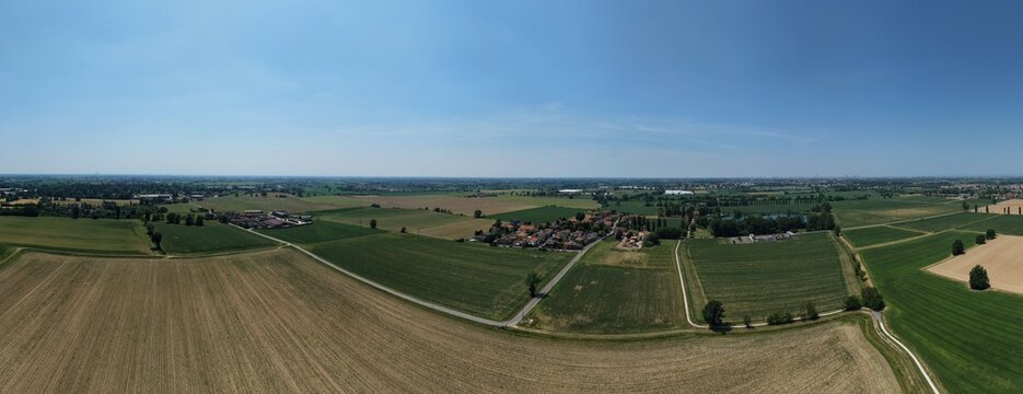 Panoramic Farmland Landscape: An expansive aerial view showcases a patchwork of agricultural fields under a clear blue sky, San Martino Olearo, Milan, Italy