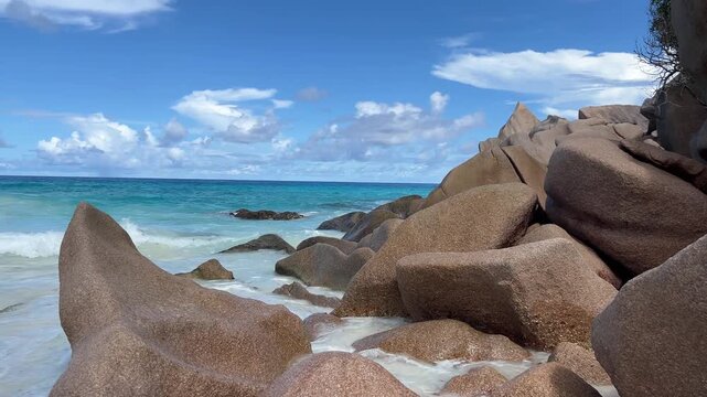 The waves of the Indian Ocean crash against large boulders on the coast of Seychelles, creating beautiful foam