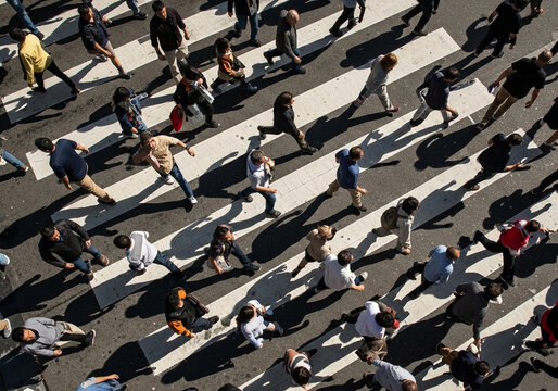 Busy city intersection filled with pedestrians crossing the street during the daytime. Urban environment with diverse individuals.