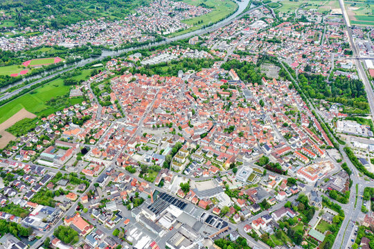 Aerial view of the historic old town of Forchheim with its dense red-roofed buildings, lush green parks, and the Regnitz river in the background in Forchheim, Bavaria, Germany.