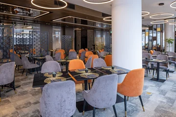 Fotobehang Horeca Contemporary hotel dining room with orange and grey chairs and geometric screens  © rilueda