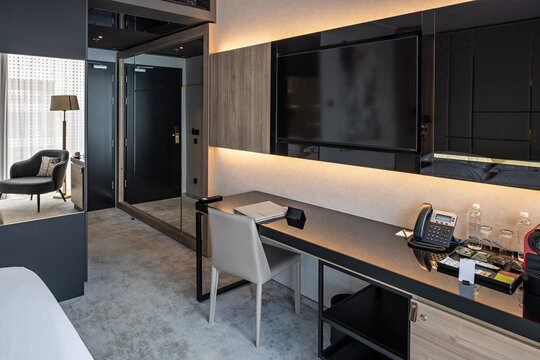 Modern hotel room workspace with desk chair flat screen tv and mirror