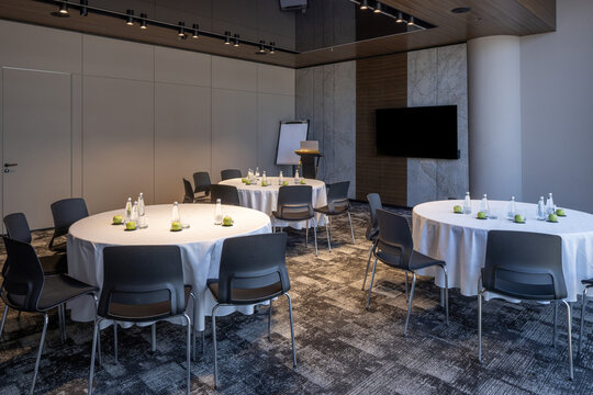 Empty corporate meeting room with round tables and white tablecloths for seminar