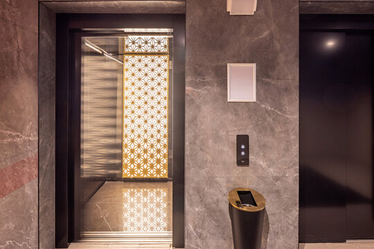 Luxury elevator entrance with marble wall and decorative gold backlit screen