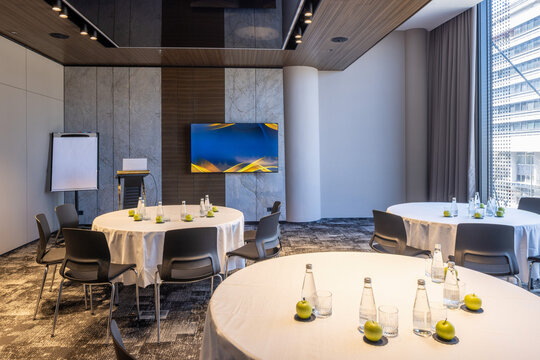 Conference meeting room setup with round tables chairs and television screen