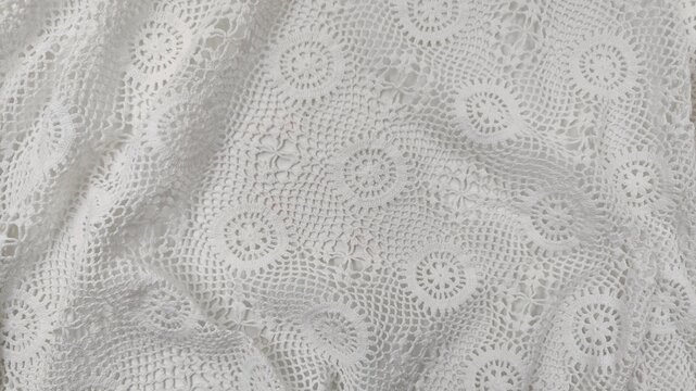 Background view of an elegant white vintage crochet lace textile with intricate handmade needlework, a full frame background texture.