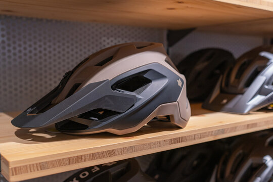 Salzburg, Austria, 05.16.2026 Close-up shot of a modern gray bicycle helmet for enduro or mountain biking, resting on a wooden shelf in a sports shop. Professional protective gear.
