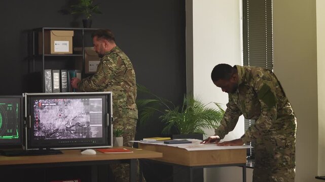 Army officers planning military mission using topographic maps in control room