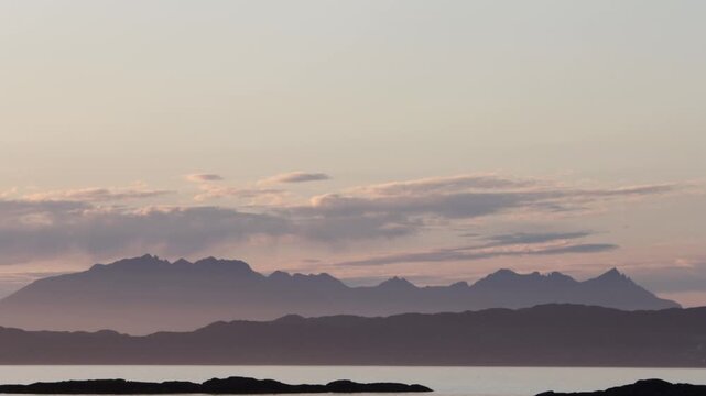 Silhouette of distant mountains on Skye, Scotland at dusk surrounded by sea mist