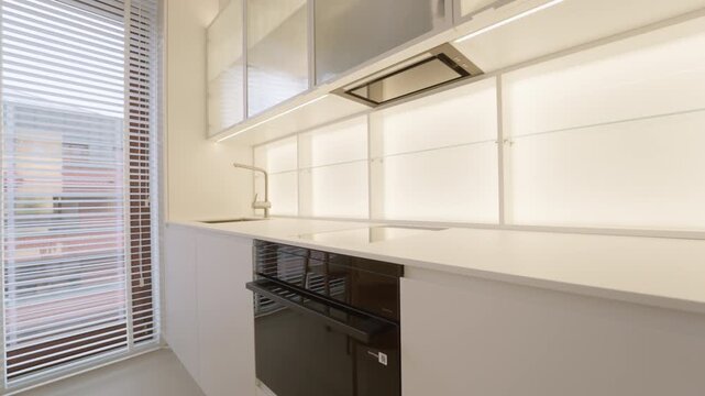 Kitchen household appliance installation inside empty apartment room features oven induction cooktop extractor hood water faucet sink near window blinds daylight home real estate property.