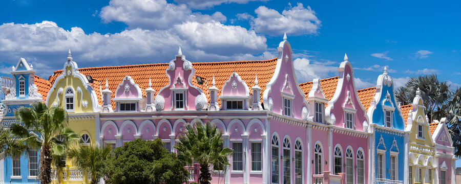 A wide panoramic shot of colorful pink yellow and blue Dutch colonial style architectural facades in downtown Oranjestad Aruba Caribbean vacation destination