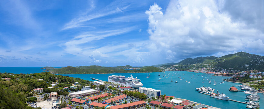 A wide panoramic high angle shot of Charlotte Amalie bay, the cruise ship dock, and downtown waterfront surrounded by tropical green hills in St Thomas USVI