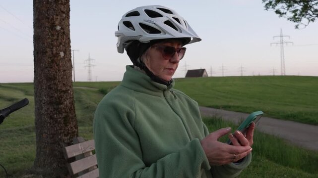 Woman cyclist checking map on smartphone during evening e-bike ride 
