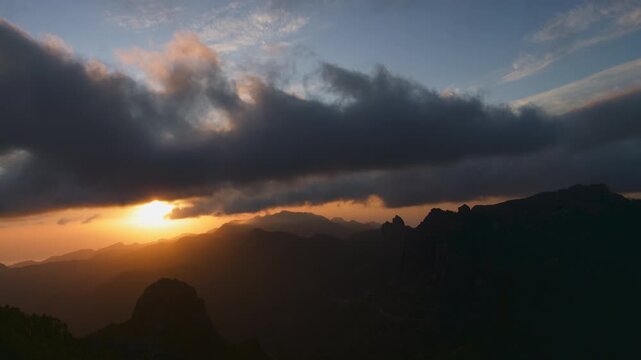 Dramatic timelapse of a beautiful golden sunset behind the mountain silhouettes of Gran Canaria, with dark clouds moving across the sky