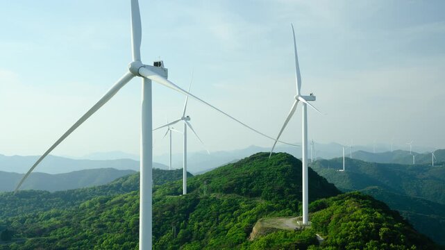 Timelapse of a Wind Turbine Farm on a Forested Mountain Ridge at Golden Hour. Wind turbines generate clean renewable energy.