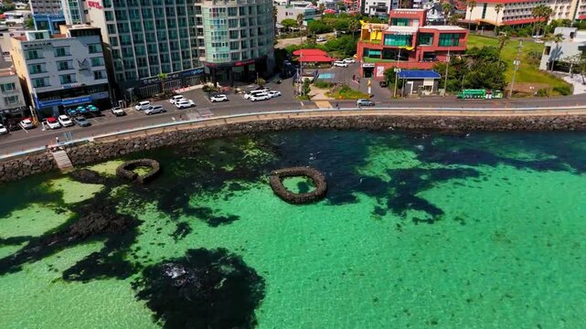 Aerial drone view of Hamdeok coastline with traditional Wondam stone fish traps, harbor and emerald turquoise sea, Jeju Island, South Korea