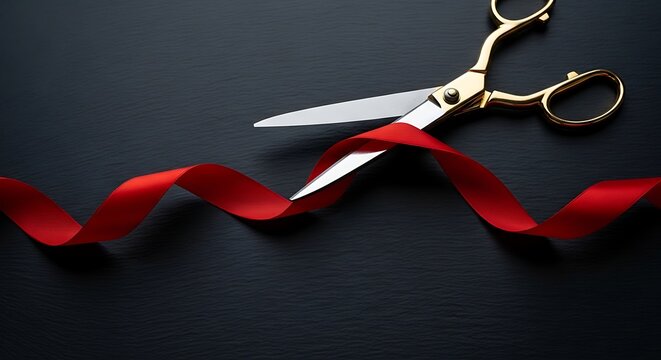 Elegant gold scissors cutting red ceremonial ribbon on dark slate background surface