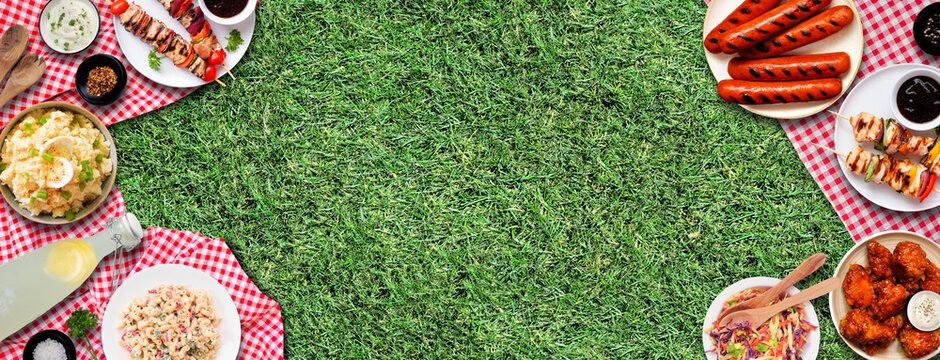 Outdoor summer BBQ food double border on a red and white check cloth and grass banner background. Variety of grilled meats, salads and sides. Above view. Copy space.