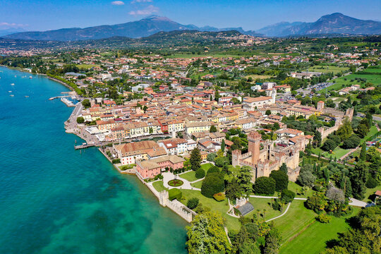 Aerial view of the historic Scaligero Castle and colorful lakeside buildings along the turquoise waters of Lake Garda in Provincia di Verona, Veneto, Italy.