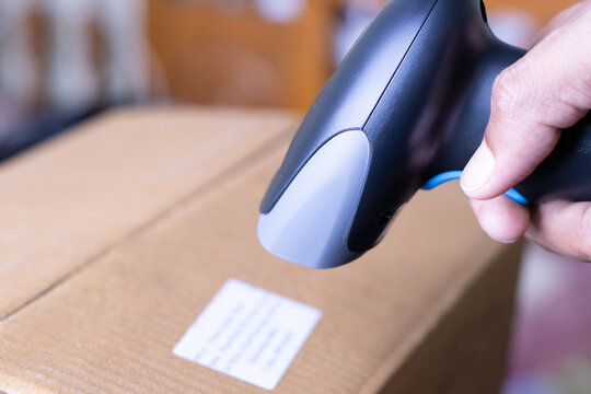 Worker Scanning Barcode on Paper Document Over Package Box for Warehouse and Shipping Management