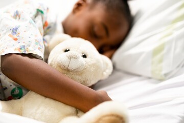 Child sleeping peacefully, hugging a teddy bear. Cozy scene with a teddy bear, child resting. Soft teddy bear, child asleep, peaceful atmosphere. African American kid sleeping, hugging teddy bear. © Rawpixel.com