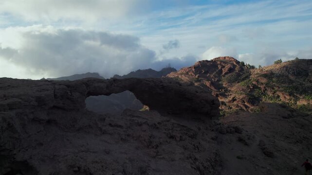Dramatic cloudy sky moving over the iconic Ventana del Nublo, a natural stone arch overlooking the mountainous landscape of Gran Canaria