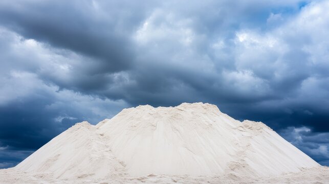 Imposing white salt mountain under a dramatic, dark blue cloudy sky. Stark contrast, raw material beauty meets powerful weather. Industrial vista. Saltworks, Stormy