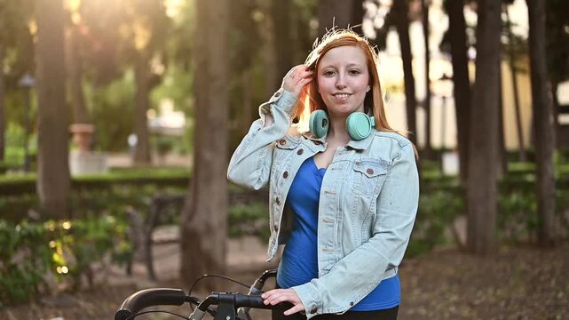 Smiling and happy young woman with mobility walker looking at camera in park, headphones around neck, inclusive portrait, disability representation, confidence, independence and accessible lifestyle