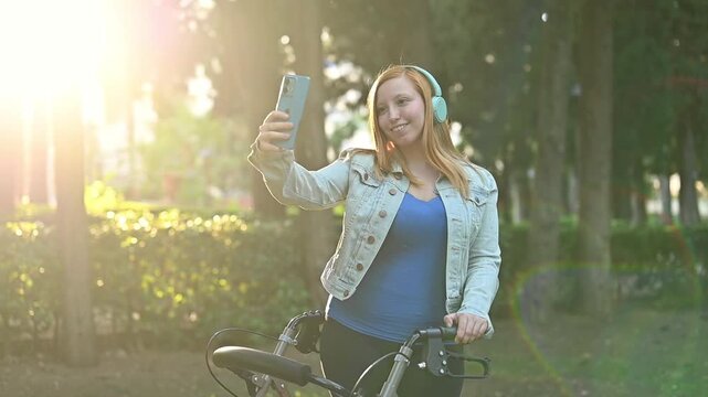 Young disabled woman with mobility walker listening to music and taking selfie at sunset in park, freedom, self care, wellness, resilience, accessible lifestyle and mental health concept