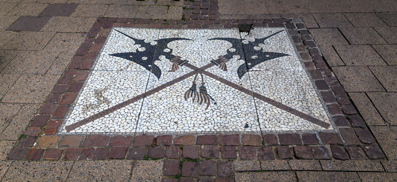 Decorative cobblestone floor mosaic of two crossed halberds set in a pedestrian pavement street in Strasbourg, France