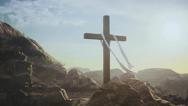 Wooden cross with white cloth blowing in the wind on a rocky hill at sunrise
