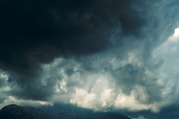 Obraz premium Thick dark clouds fill sky, showing signs of approaching storm. mix of gray and white in clouds. time is late afternoon. Dark clouds gather in sky over landscape suggesting storm is coming in