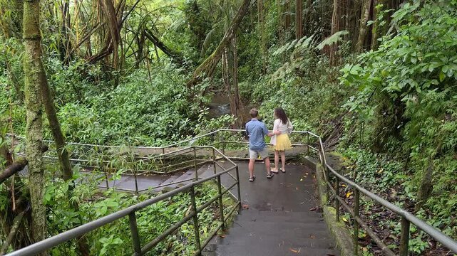 Young couple enjoying walking alone in tropical rainforest stop to take photo