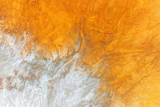 Aerial view of the vibrant orange iron-rich soil and cracked earth textures at the historic mining site Minas de Riotinto, Andalusia, Spain.